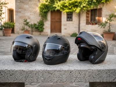 Trois casques moto d'été alignés sur un banc en pierre : casque jet, intégral ventilé et modulable avec aérations ouvertes