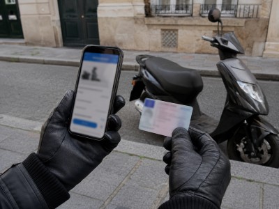 Conducteur de scooter vérifiant la vignette Crit’Air de son 50cc sur smartphone avec carte grise