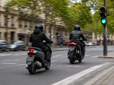 Scooter 50cc et 125cc au démarrage d’un feu en ville, accélérations contrastées sur un boulevard européen